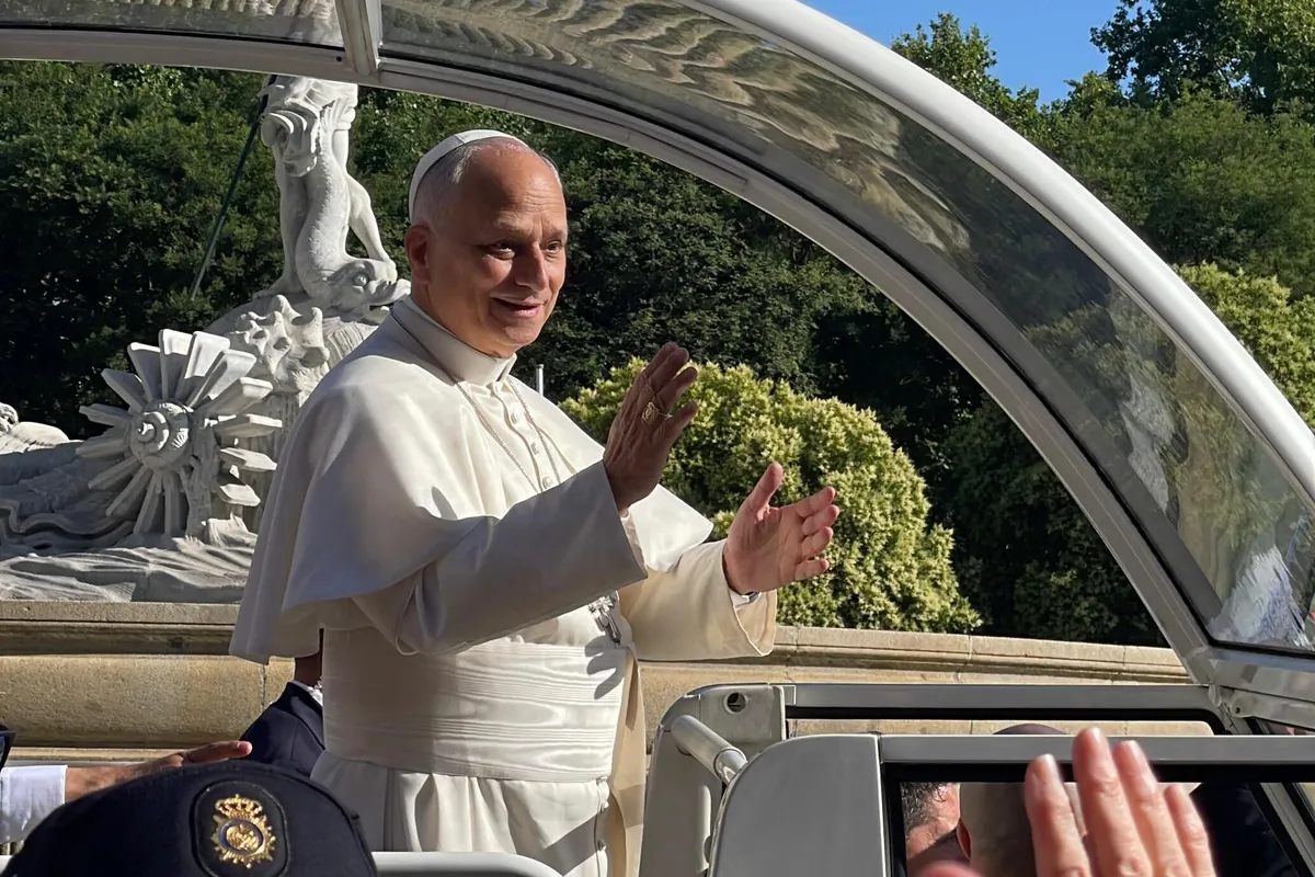 El papa León XIV, sonriente y vestido de blanco, saluda con las dos manos en alto desde el papamóvil, bajo su techo transparente.