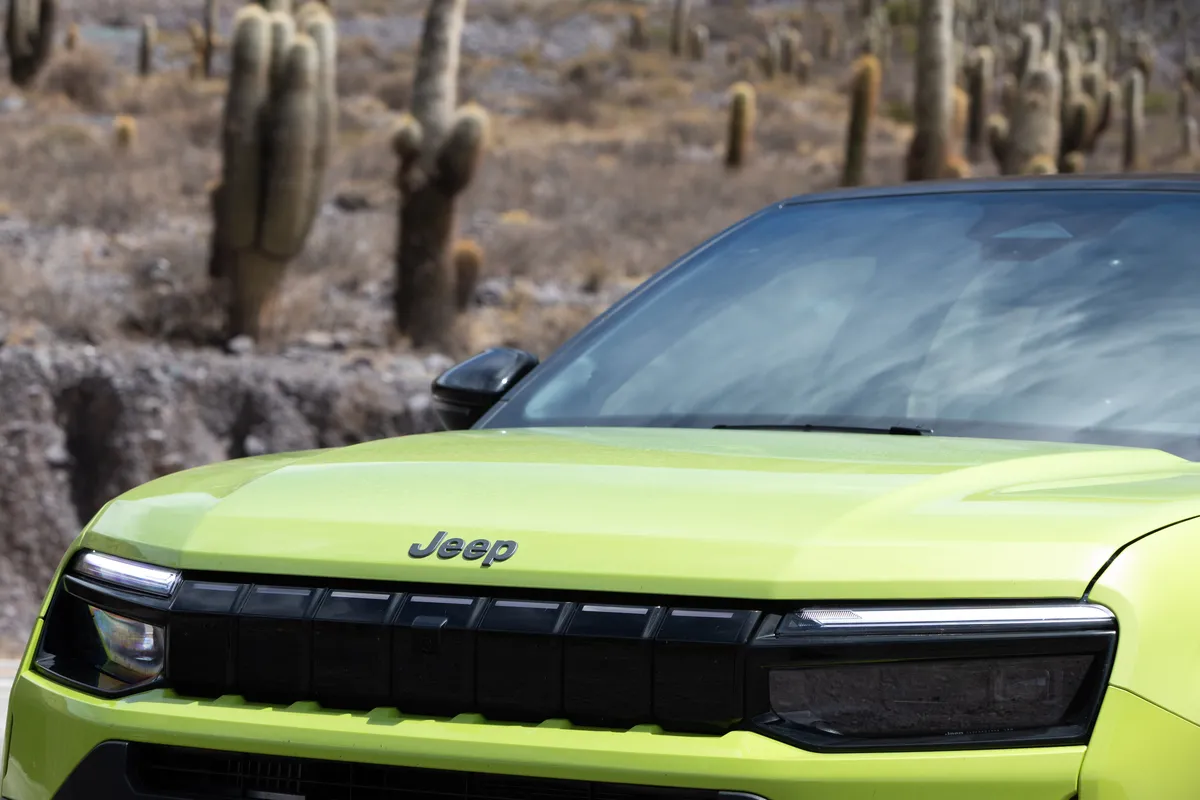 Primer plano de la trompa de un Jeep Avenger verde, con el logo en el capó y la parrilla negra.