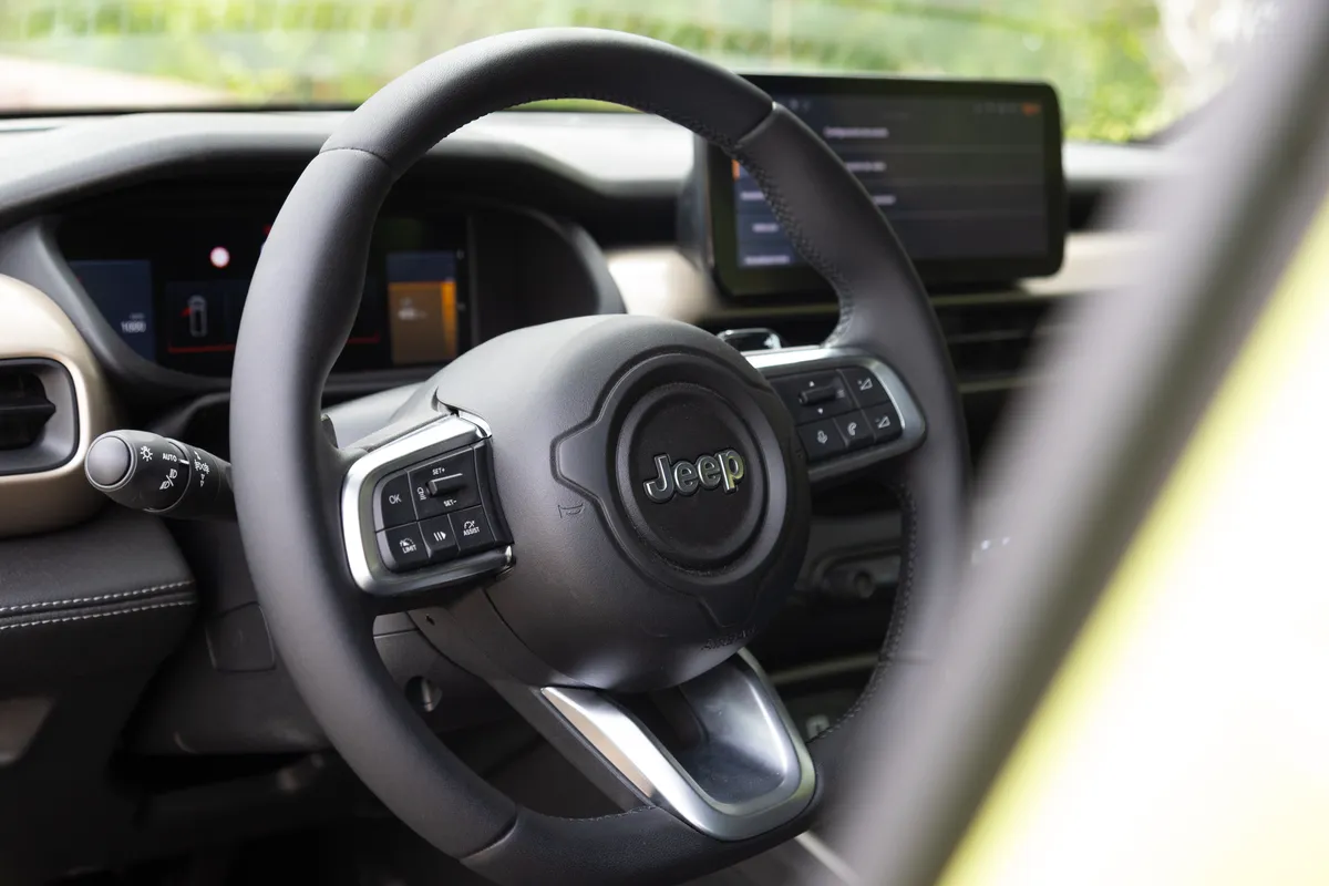 Detalle del volante y parte del tablero de un Jeep Avenger, con terminaciones plateadas.
