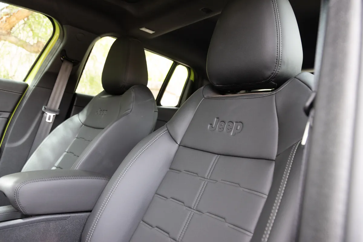 Las butacas delanteras de un Jeep Avenger, tapizadas en gris oscuro con el logo de Jeep en relieve, vistas por la puerta abierta.