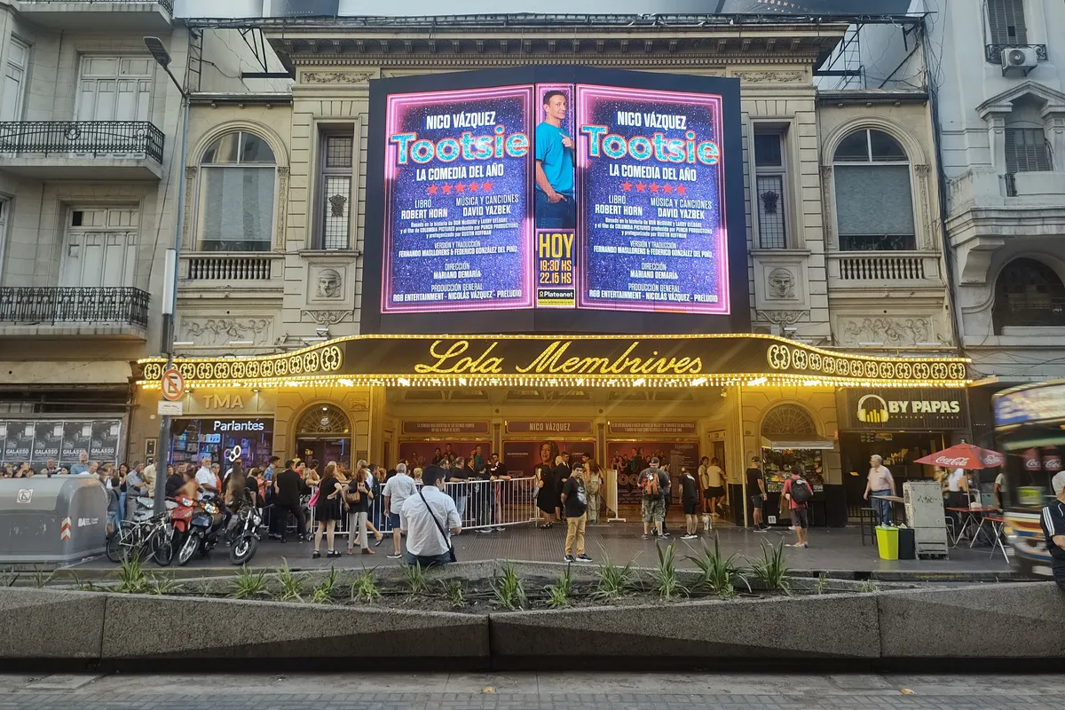 La fachada clásica color crema del teatro Lola Membrives, con su marquesina iluminada en letras doradas, un gran cartel de la obra Tootsie con el nombre de Nico Vázquez y público reunido en la vereda de avenida Corrientes.