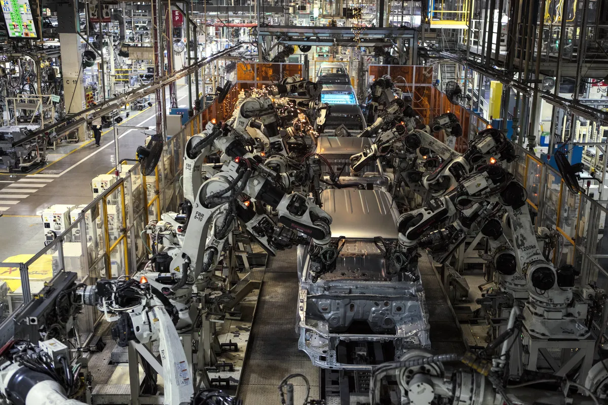 Robots industriales blancos rodean carrocerías de pick-up sin pintar en una línea de soldadura de la planta de Toyota en Zárate.